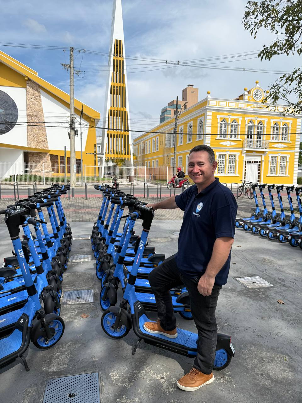 Frota de patinetes JET organizada em praça urbana com equipe da operação